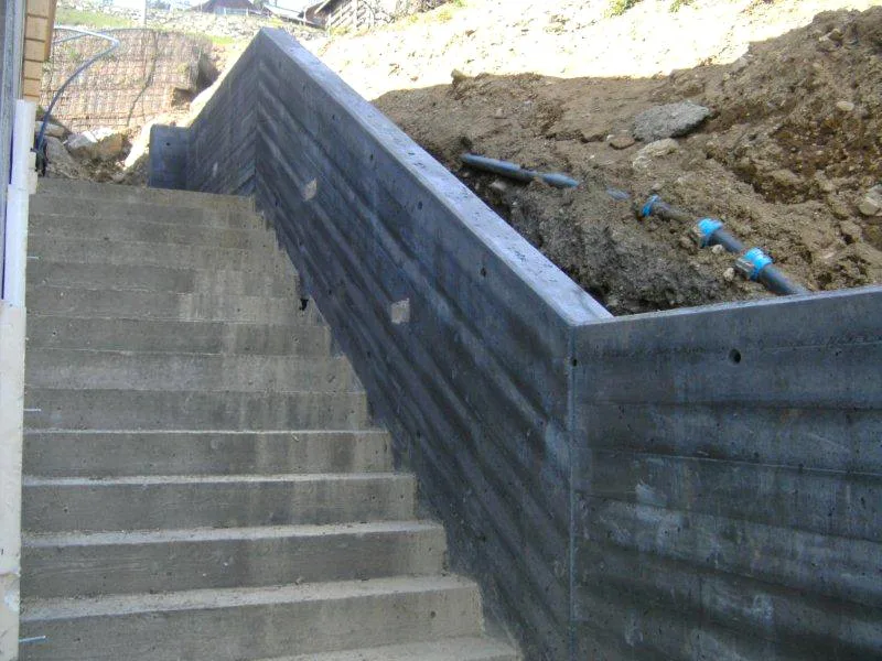 Betontreppe mit seitlicher Stützmauer, die einen Hang hinaufführt
